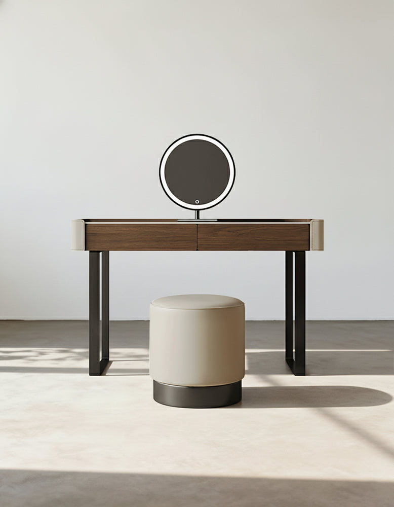 Dresser with round mirror and stool against a white wall