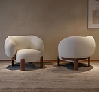 Two modern chairs with wooden legs in a room with a neutral wall and carpet.