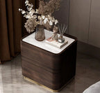 Wooden nightstand with decorative items including a vase of flowers and a figurine.