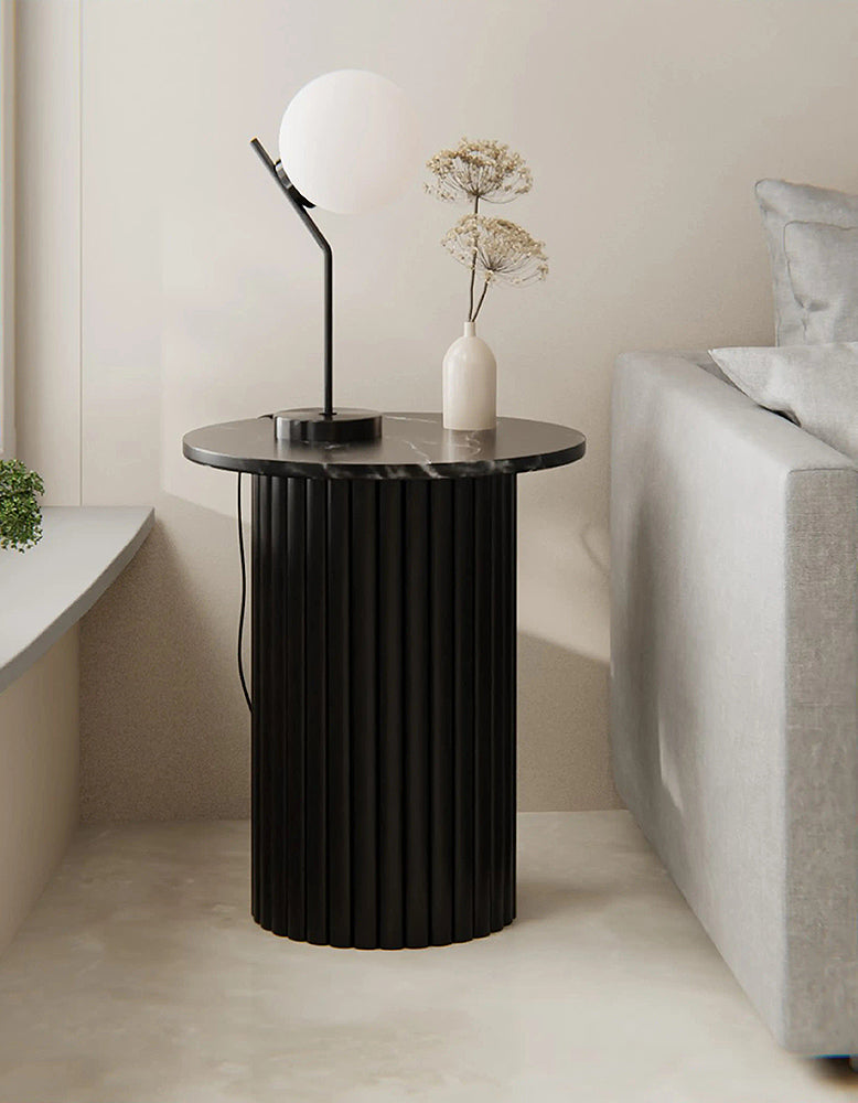 Modern black side table with a lamp and vase in a minimalistic living room.