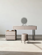 Beige vanity table with mirror and stool in a minimalistic room.