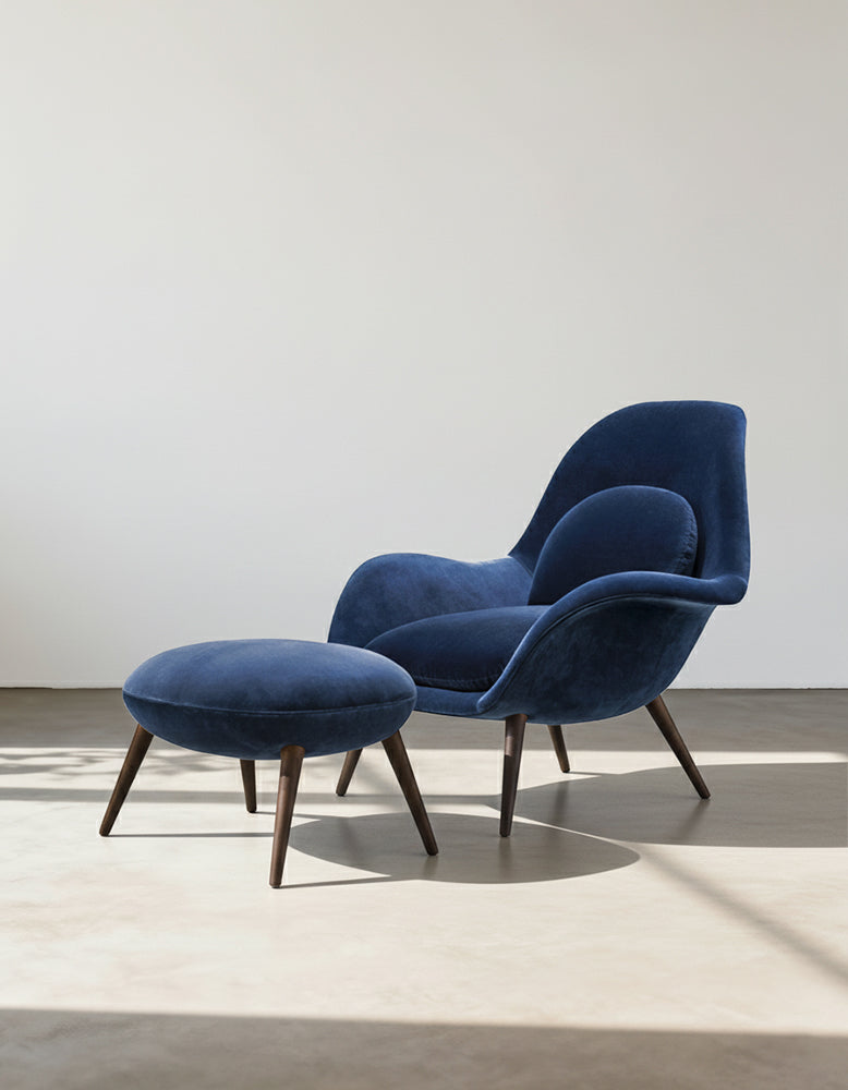 Blue velvet armchair with matching ottoman on a neutral background