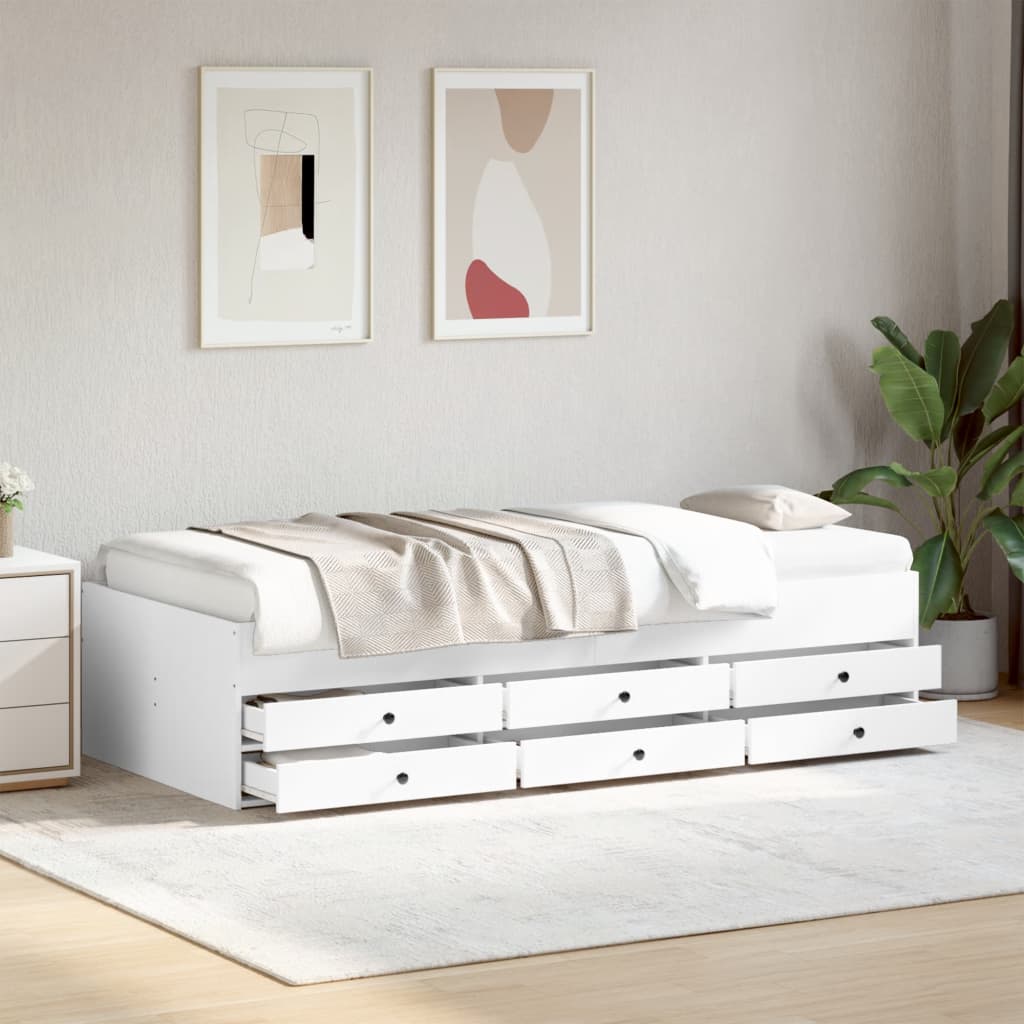 White bed with storage drawers in a room with abstract art and a plant.