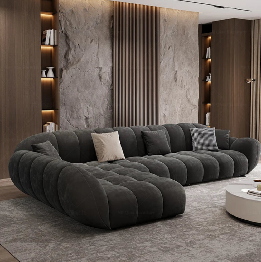 Modern living room with a large gray sofa against a neutral wall.