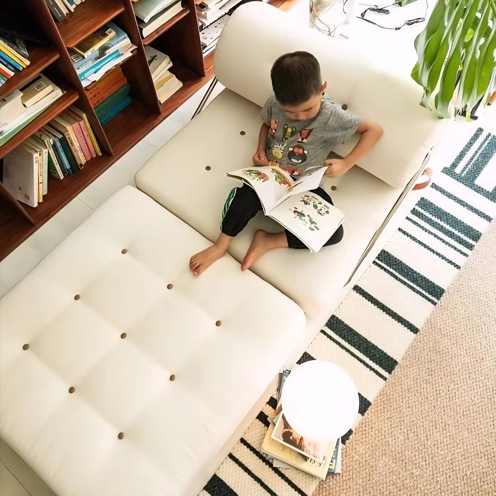 Child reading a book on a white couch in a cozy living room.