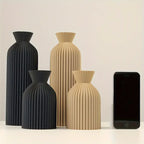 Set of black and beige vases with a smartphone for scale on a light background