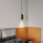 Modern pendant light fixture hanging above a bed in a bedroom with orange accent wall.