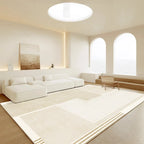 Modern living room with white sofa, rug, and large windows.
