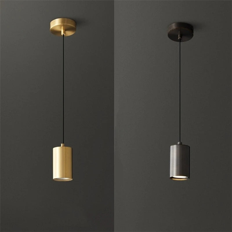 Two pendant lights, one gold and one silver, against a dark gray background.