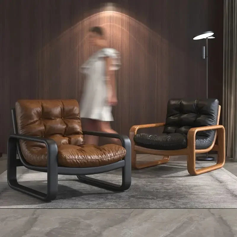 Two modern chairs, one brown and one black, in a room with a blurred person in the background.