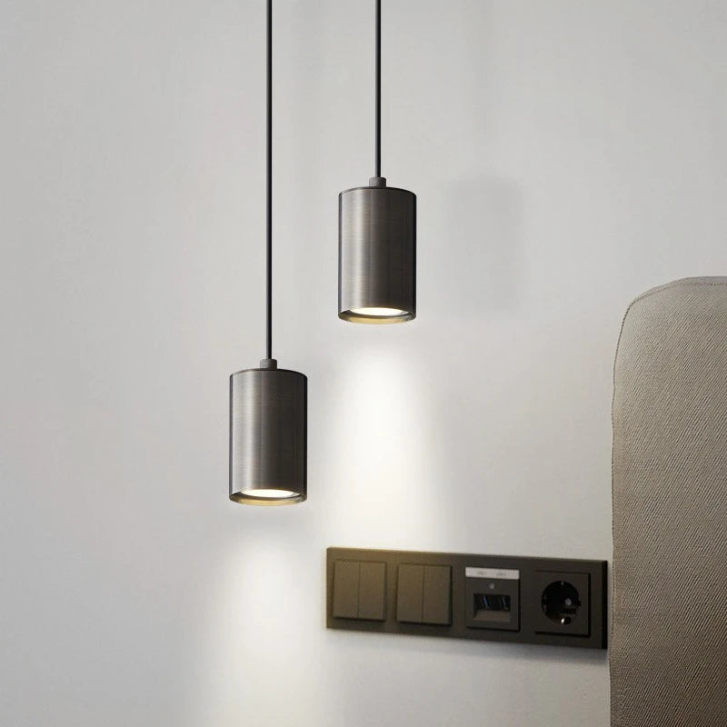Two pendant lights hanging from the ceiling with a wall socket below on a light gray wall.