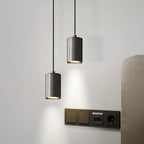Two pendant lights hanging from the ceiling with a wall socket below on a light gray wall.