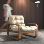 Beige armchair with wooden frame in a room with a blurred person and lamp in the background