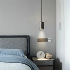 Modern bedroom with gray bed, pendant light, and nightstand with clock.