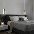 Modern bedroom with gray bedding, white pillows, and pendant lights.