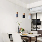 Modern dining area with white table, chairs, and pendant lights in a kitchen setting.