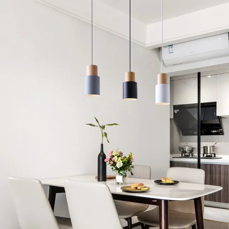 Modern dining area with white table, chairs, and pendant lights in a kitchen setting.