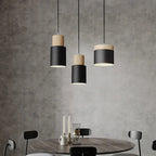 Modern pendant lights hanging above a dining table with a concrete wall background