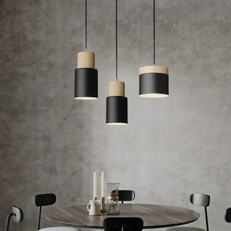 Modern pendant lights hanging above a dining table with a concrete wall background