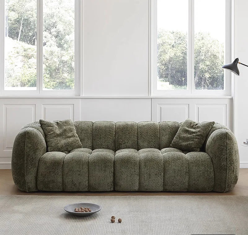 Green sofa in a room with large windows and a light-colored rug.