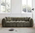Green sofa in a room with large windows and a light-colored rug.