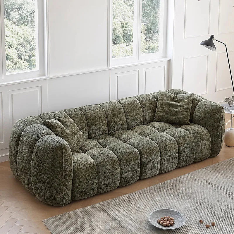 Green sofa in a room with large windows and a lamp.
