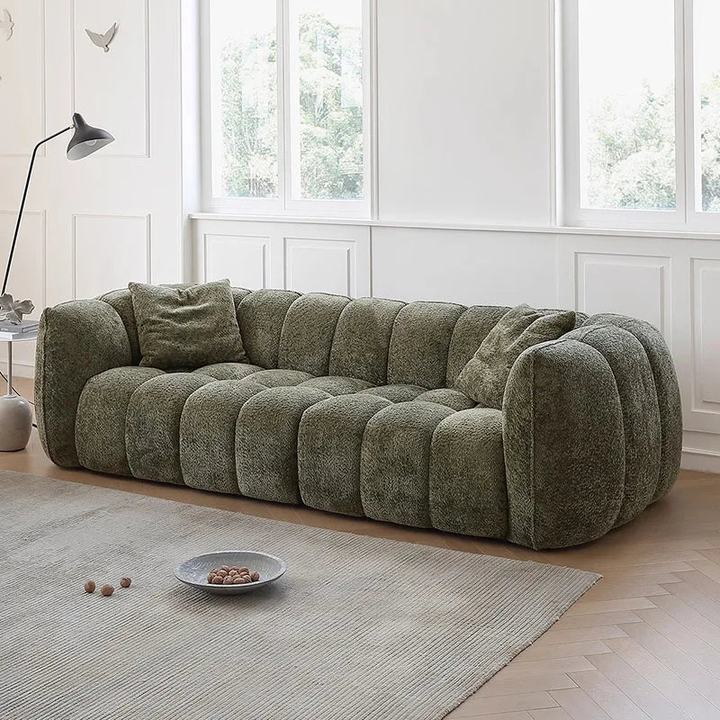 Green sofa in a room with large windows and a rug.