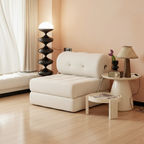 Modern living room with a white sofa bed, side table, and decorative items.