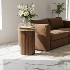 Brown sofa with a wooden side table and floral arrangement in a modern living room.