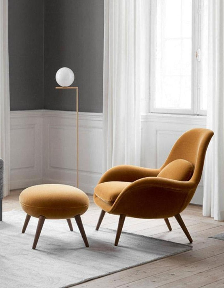 Brown armchair and ottoman in a room with a lamp and window.