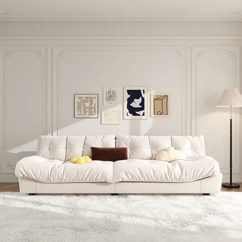Modern living room with a white sofa, decorative pillows, and framed art on the wall.