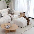 Modern living room with a white sofa, ottoman, and wooden coffee table.