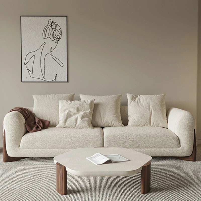 Beige sofa with cushions in a living room setting, featuring a coffee table and wall art.