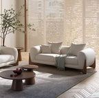 Modern living room with white sofa, armchair, and coffee tables.