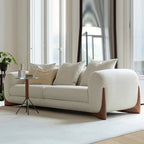 White sofa in a modern living room with large windows and a small table.