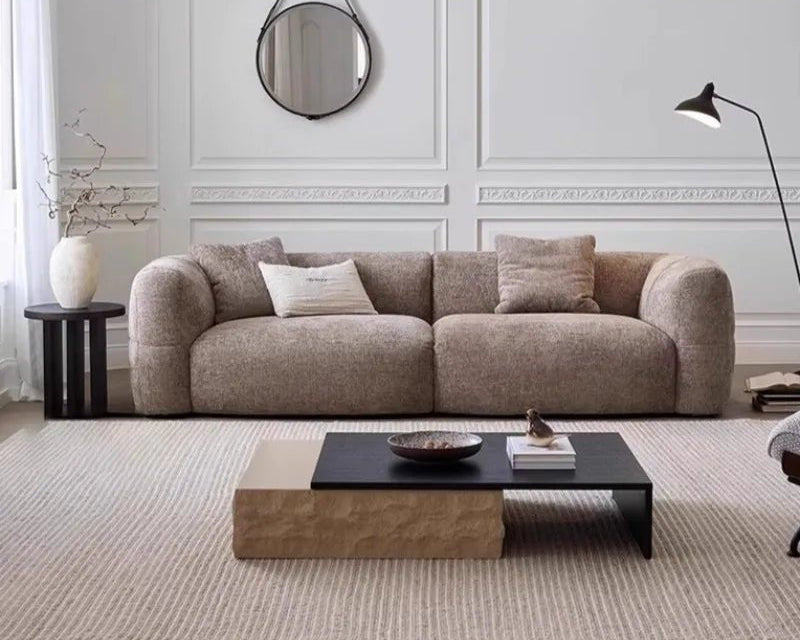 Modern living room with a beige sofa, coffee table, and decorative items.