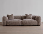 Brown sofa with two cushions on a wooden floor and gray wall background