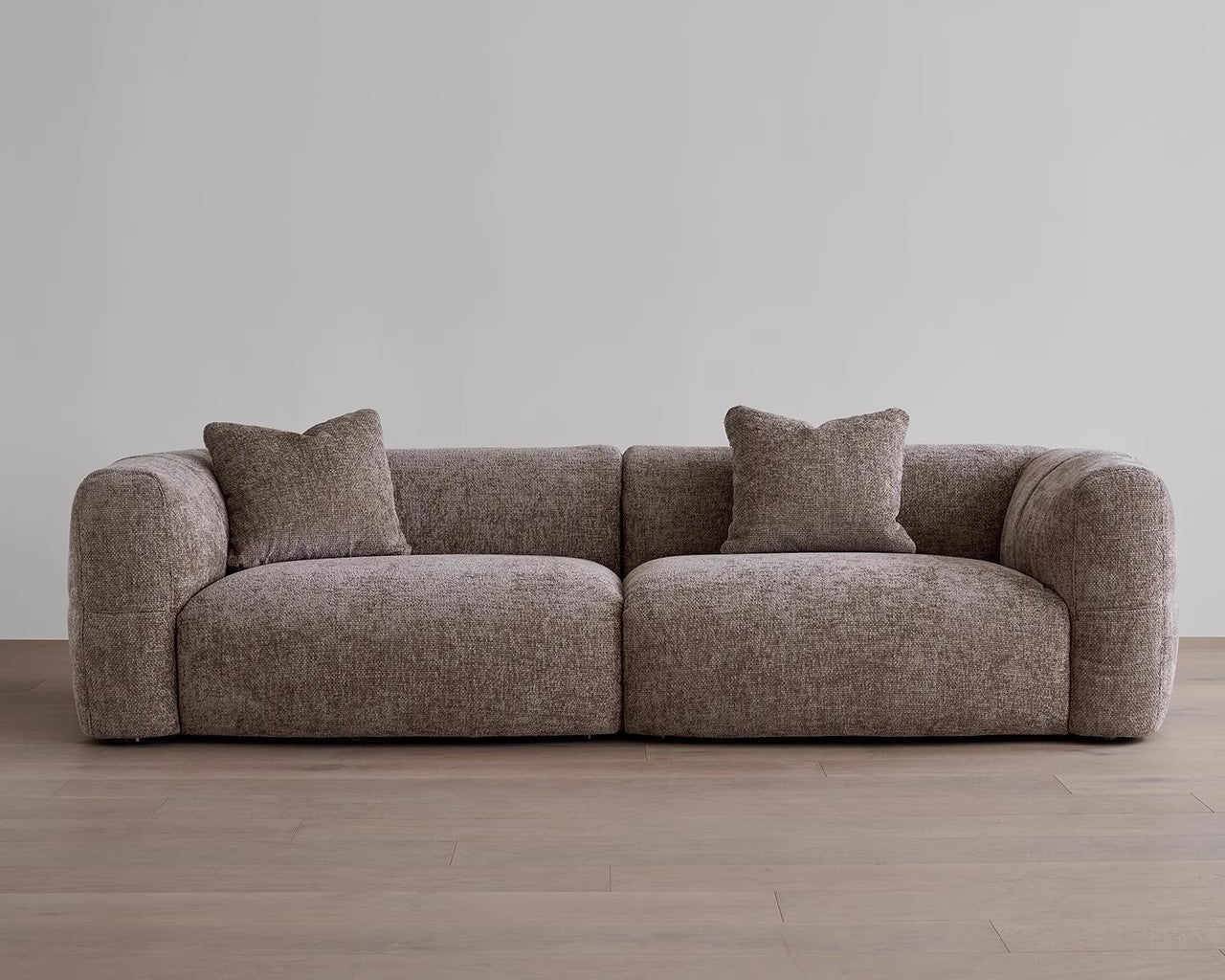 Brown sofa with two cushions on a wooden floor and gray wall background